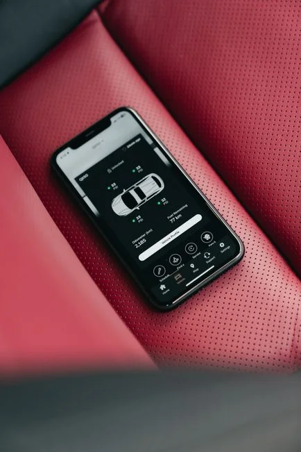 Vue rapprochée d’un smartphone avec un stylet posé sur une surface rouge éclatante, mettant en avant la technologie moderne.